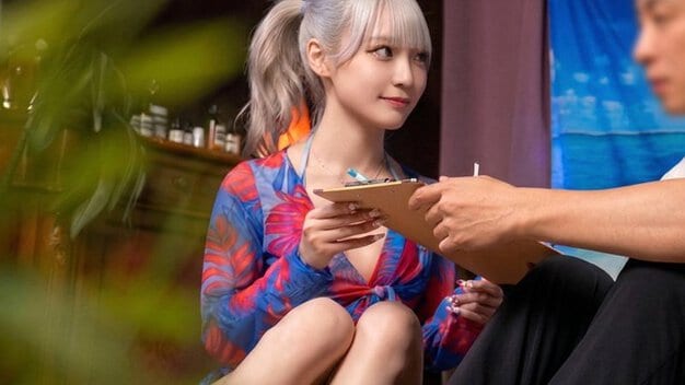 美菜ちゃんが胸元の開いた服でしゃがみ、アンケート用紙を持って男性に笑顔を向ける