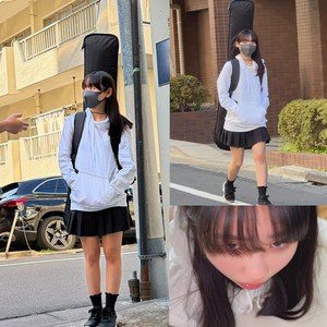 黒い長髪の女性がグレーのマスク、白いパーカー、黒いプリーツスカート、黒い靴下と靴を着用し、ギターケースを背負って道路に立ち、ポケットに手を入れている。歩く姿や顔のアップも確認できる。
