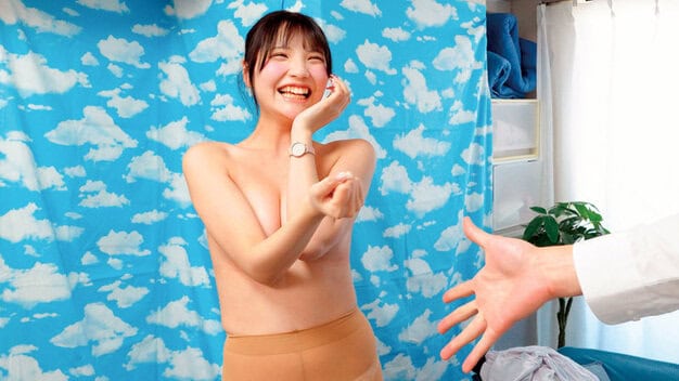 黒髪の女性が上半身裸でスカートを着け、左手を頬に当て右手でグーを出し、口角が上がっている。